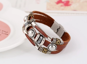 Close-up of multilayer brown leather bracelet featuring silver studs and magnetic buckle