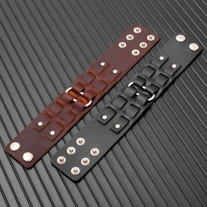 Dettaglio di ampi bracciali punk in pelle con borchie in metallo e bottoni a pressione