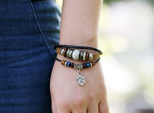 Détail d'un bracelet multicouche en cuir avec lanières tressées et pendentif feuille