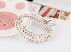 Close-up of a white multi-layer woven leather bracelet with a silver metal hook clasp