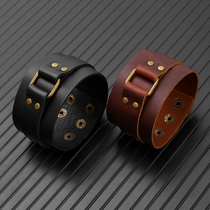 Detail view of adjustable black and brown leather wristbands with bronze rivets and snaps