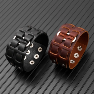 Dettaglio di bracciali larghi in pelle nera e marrone regolabili con anelli in metallo
