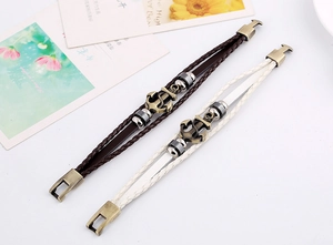 Detail of multi-layer leather bracelets featuring bronze anchor charms and clasp closure