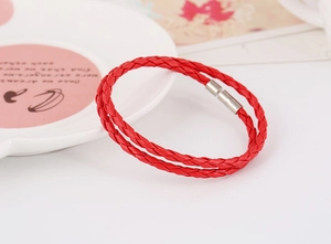Detail of red braided leather bracelet featuring a silver magnetic cylinder clasp