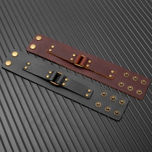 Detail of adjustable leather bracelets in black and brown with vintage rivets