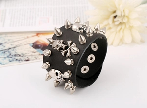 Detail of black leather punk bracelet with silver skulls and metallic cone spikes