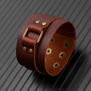 Macro view of vintage brown leather cuff featuring bronze studs and buckle detail