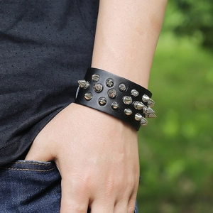 Detail of a wide black leather punk bracelet with three rows of silver spikes