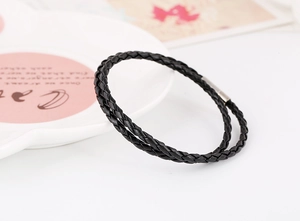 Detail of black double-wrap braided leather bracelet with silver magnetic metal clasp