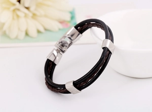 Detail of layered braided leather bracelet with silver metal sliders and mechanical clasp