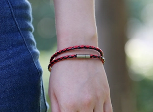 Detail of red and black braided leather bracelet with silver magnetic clasp on wrist