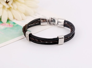 Detail of multi-layer leather bracelet with silver metal charms and secure clasp