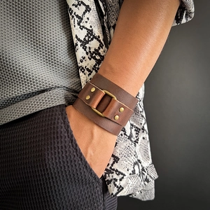 Vintage dark brown leather wide cuff bracelet with brass rings on male wrist