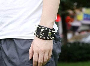 Detail of punk leather bracelet with metal spikes and skull charms on wrist