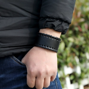 Detail of wide black punk leather wristband with braided edges on a male model