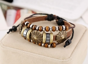 Detail of vintage multilayer leather bracelet with wooden beads and star engraved metal charm