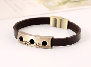 Macro view of vintage brown leather bracelet with embossed bronze cross metal plate