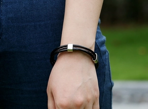 Close-up of a woven dark brown leather bracelet featuring a sleek silver magnetic buckle