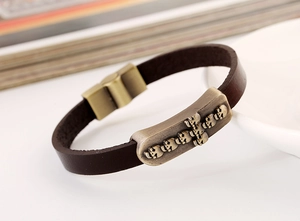 Detail of vintage brown leather bracelet with bronze skull charms and magnetic clasp