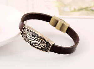 Macro detail of dark brown leather bracelet featuring bronze alloy wing emblem and clasp