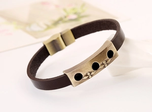 Detail of vintage men's leather bracelet featuring cross engraved antique bronze plate