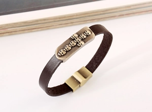 Detail view of brown leather punk bracelet featuring bronze skull plate and magnetic clasp