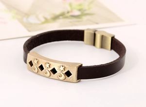 Detail of star and moon alloy plate on vintage dark brown leather bracelet