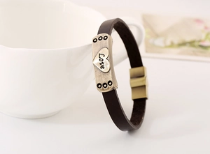 Détail d'un bracelet en cuir marron vintage avec plaque cœur Love et fermoir aimanté