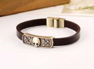 Close-up of vintage bronze skull plaque on dark brown leather bracelet with magnetic clasp