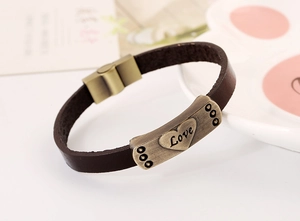 Détail d'un bracelet en cuir marron foncé avec boucle magnétique en bronze et motif de coeur