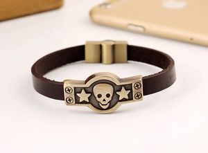 Détail macro de l'emblème tête de mort en bronze sur un bracelet punk en cuir marron