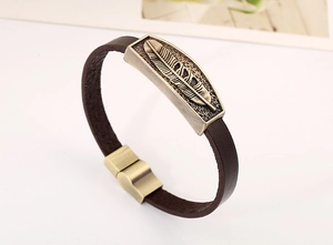Detail of vintage bronze feather charm and magnetic clasp on brown leather bracelet