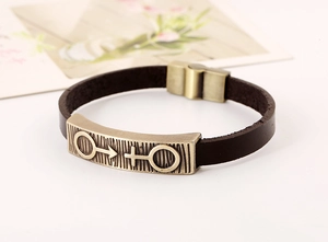 Macro detail of brown leather bracelet with bronze gender symbols and magnetic clasp