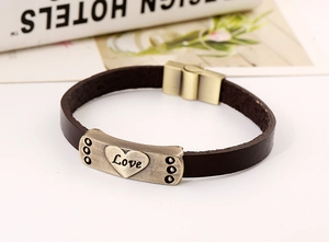 Gros plan du charme Love en or vintage sur bracelet en cuir marron avec fermoir aimanté