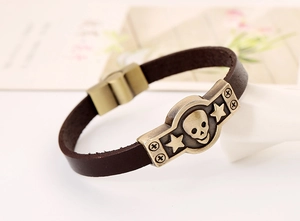 Vue détaillée d'un bracelet punk en cuir avec crâne en bronze et charmes métalliques