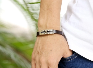 Close-up of a vintage leather bracelet for men featuring a golden cross buckle