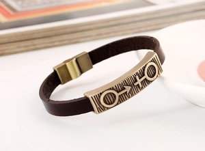 Close-up of vintage brown leather couple bracelet with bronze metal charm and magnetic clasp