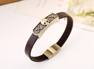 Detail of vintage brown leather bracelet with bronze skull plaque and magnetic clasp