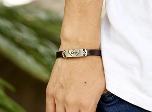Détail d'un bracelet en cuir véritable marron avec breloque cœur en laiton gravée Love
