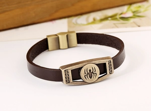 Close-up of spider emblem on vintage brown leather bracelet with magnetic buckle