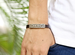 Detail of a brown leather bracelet with an engraved bronze alloy gender symbol tag