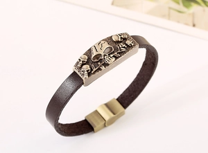 Dettaglio macro del bracciale punk in pelle da uomo con cinque teschi in bronzo a rilievo