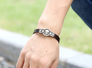 Gros plan d'un bracelet en cuir marron foncé de style punk avec plaque en bronze et crâne