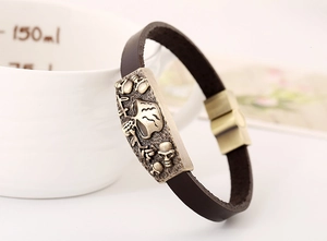 Dettaglio del bracciale in pelle marrone con rilievo di teschio in bronzo e chiusura magnetica