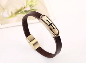 Detail of vintage brown leather bracelet with brass cross hollow metal plate