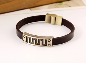 Detail of vintage brown leather bracelet with antique bronze geometric metal plate