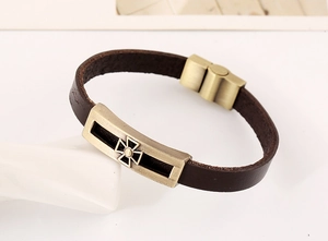 Detail of vintage brown leather bracelet with bronze alloy cross plate and metal clasp