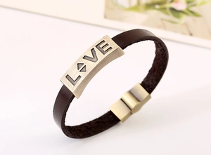 Detail of vintage brown leather bracelet with bronze LOVE metal plate and magnetic clasp