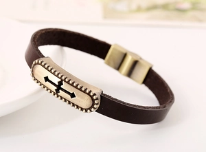 Detail of vintage brown leather bracelet featuring a bronze magnetic clasp and cutout metal charm