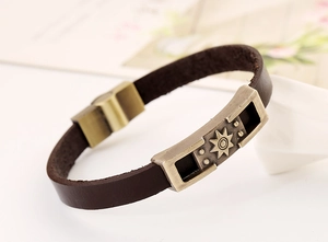 Detail of vintage leather bracelet with antique bronze sunburst metal piece and magnetic clasp